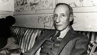 The writer, William Burroughs, at a dive bar dressed in a three-piece suit