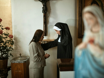 Una mujer y una monja rezando en una iglesia