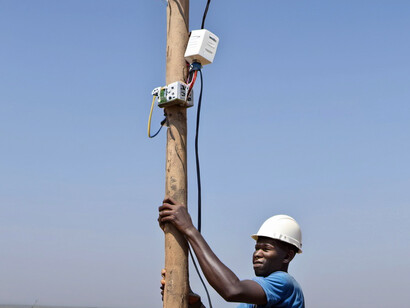 An electrician attaches a cable to a new internet pole, helping to extend digital connectivity to areas previously left out of the technological revolution