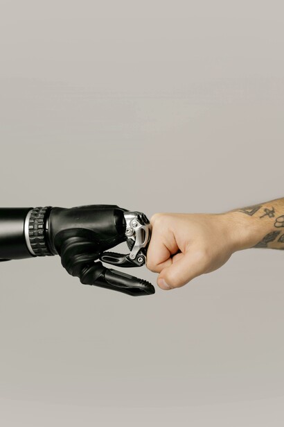 A human and robotic hand connect in a fist bump symbolizing an evolving relationship