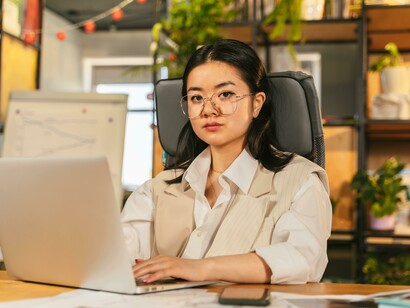 A confident businesswoman works on her laptop in the office, focused and in control