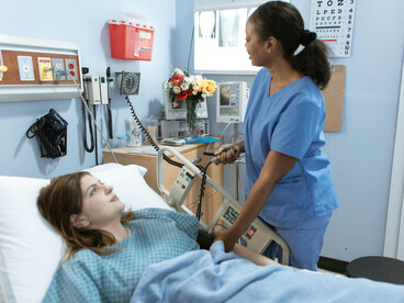 A well-equipped hospital. The patient lies on the bed, and her vital signs are being checked by a nurse