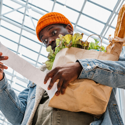An African American man checks his receipt after shopping, reflecting the impact of inflation and household budget struggles