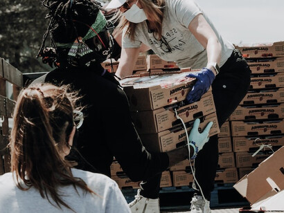 A compassionate woman volunteer unpacking a truckload of food for the less fortunate