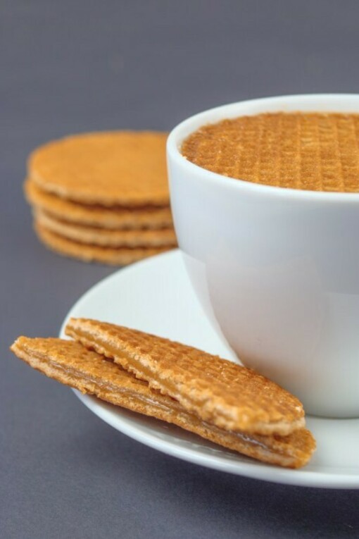 A white ceramic mug paired with stroopwafels on a matching white ceramic plate