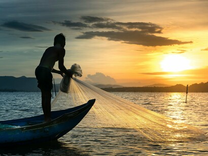 A solitary fisherman framed by the last light of day, reflecting the pursuit of survival that overshadowed youthful ambition