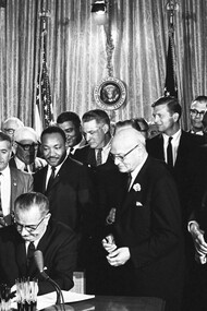 President Lyndon Johnson signs the Civil Rights Act of 1964; directly behind Johnson—Martin Luther King, Jr., Ralph Abernathy (directly behind King) and John Lewis (to the left of Abernathy)