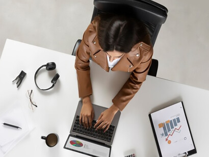 Overhead view of a female journalist typing on her laptop, focused on her work