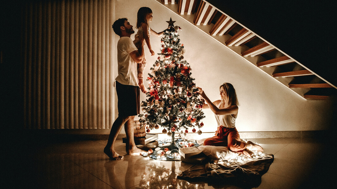 Família prepara árvore de natal e pendura decorações 