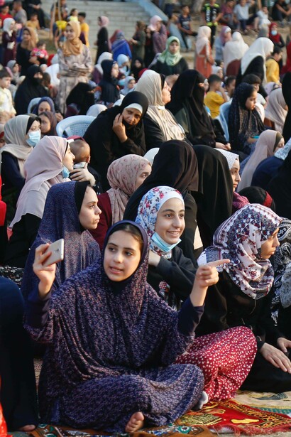 Women sit on the ground during sunset in Gaza