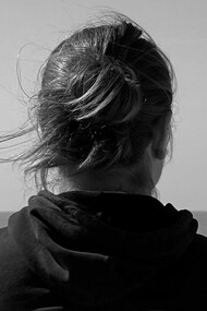 A woman looks at the horizon by the sea