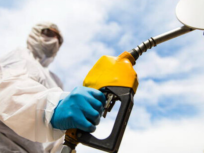 A gas station employee assists a customer with fuel as energy prices surge during the COVID-19 pandemic