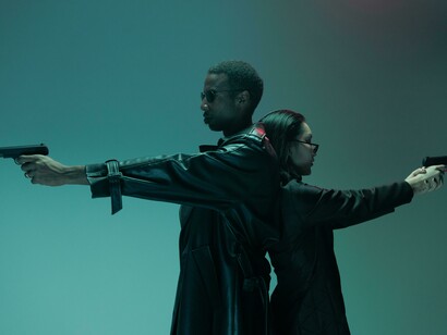 In a dystopian Matrix universe, a man and woman stand back to back, guns drawn, resisting the machines that have enslaved humanity