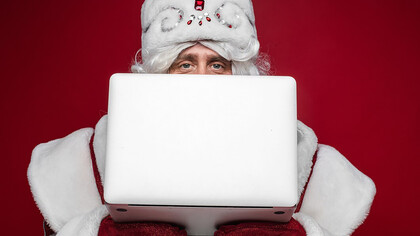 Santa Claus hiding behind laptop