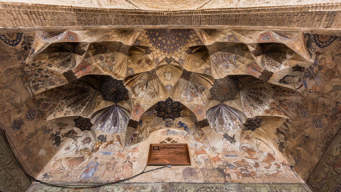 The vaulted ceiling at the entrance of the Ganjali Bathhouse, built in 1631 as part of a larger architectural complex in the old center of Kerman, Iran, features frescoes adorned with Safavid-era ornaments