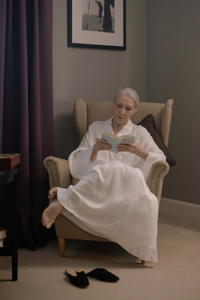 An elderly woman seated in an armchair in her home