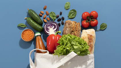 Una borsa della spesa in tela piena di prodotti freschi come verdure, frutta, pane e legumi