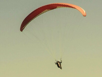 Vôo de parapente. Nina grita intensamente ao longo da descida num misto de desespero e frenesi! Um outro piloto na rampa comenta “Para descer com tanto grito tem que pagar mais caro!” e na sequência pergunta “Quem é o próximo?”