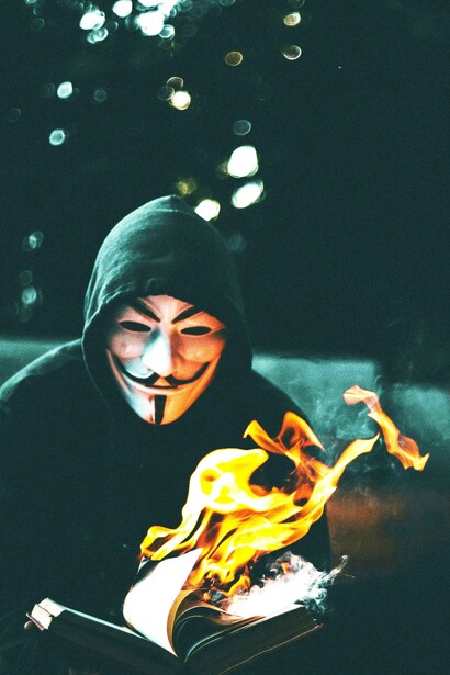A masked figure setting flowers on fire