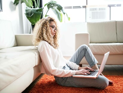 A young woman sitting on the floor while window shopping online and experiencing the nature of e-commerce