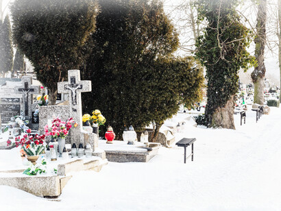 A snow-covered cemetary, with flowers left at headstones in remembrance of our loved ones who have passed