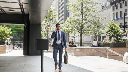 Businessman walking away from the office while speaking on the phone