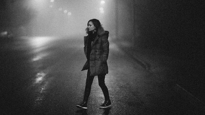 A woman walking through a dimly lit street at night