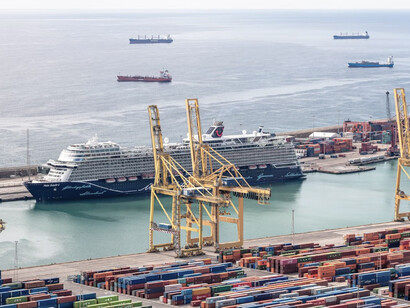 A cargo ship being loaded at a port during the day, illustrating activity along a major trade corridor