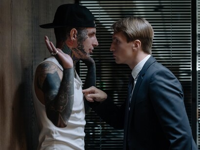 Homem executivo ameaça homem com tatuagens