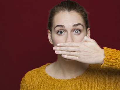 A woman covering her mouth. Self-censorship can make someone stop their voice and this does not allow someone to explore their own ideas