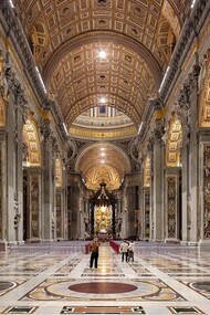 La navata centrale della Basilica di San Pietro si apre come un immenso spazio solenne e luminoso, scandito da colossali pilastri e ornato da marmi policromi e mosaici dorati, che guidano lo sguardo verso l’altare papale. Foto di Nate Bergin. Basilica di San Pietro, Città del Vaticano