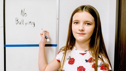 Menina escreve mensagem contra o bullying no quadro