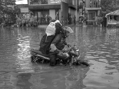 Navigating through flooded roads, he presses on, questioning how far society must descend before awakening to the looming environmental crises