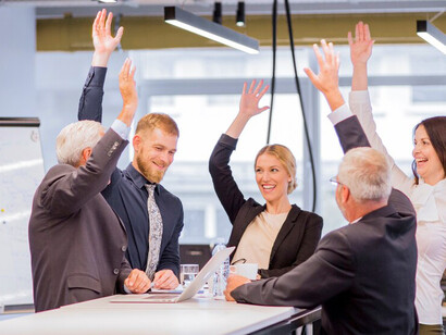 Cheerful business people raising their arms in a meeting
