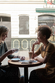 Two women share an emotional reunion in a café, laughing together