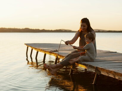 Mother and son fishing from a dock at sunset, illustrating inner serenity and miraculous consciousness that offer solace and connection
