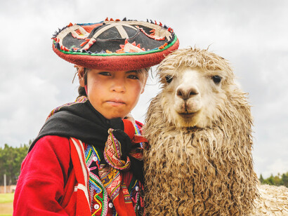 Niña aborigen junto a una llama en los pueblos originarios de Cusco en Perú