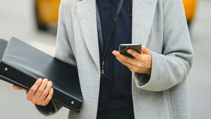 Mulher executiva utiliza o celular para trabalhar enquanto anda na rua
