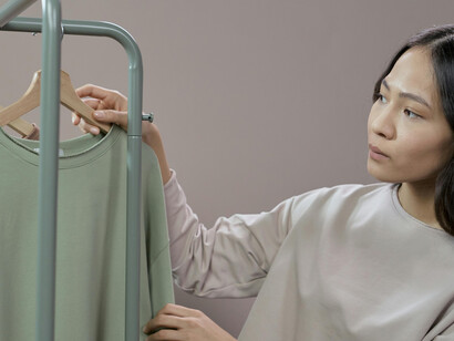 A woman looking at sweaters, symbolizing the sustainable fashion future and eco-friendly clothing movement
