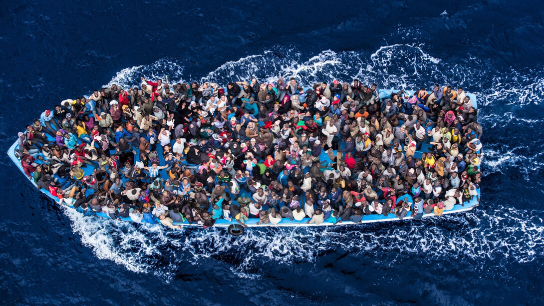Italian navy rescues asylum seekers packed into a boat off the coast of Africa on the Mediterranean Sea