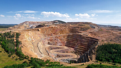 A vast open pit mining operation carved into the heart of a forest, symbolizing the destructive impact of green colonialism and the exploitation of resources in the Global South