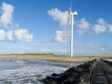 Hvide Sande, Denmark features an idyllic beach scene with wind turbines along the coast, emphasizing the presence of renewable energy