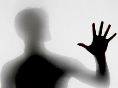 A silhouette begins to dissolve, hands reaching through shadow in a moment of transformation