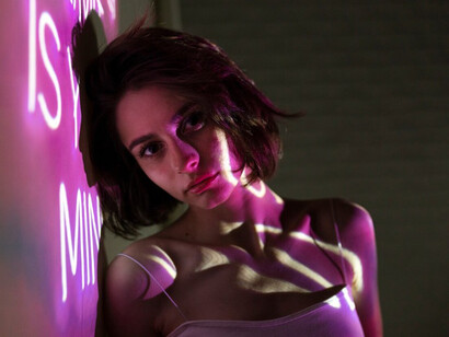 Artistic portrait of a young woman under neon lighting, reflecting the mood of contemporary performance art