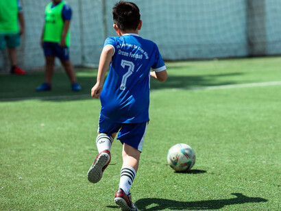A young footballer sprinting after the ball with purpose, reflecting the relentless pursuit of a World Cup dream