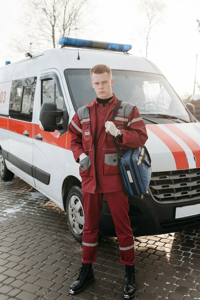 Emergency responder standing ready beside an ambulance, representing the frontline preparedness needed to protect vulnerable communities during El Niño-driven disasters