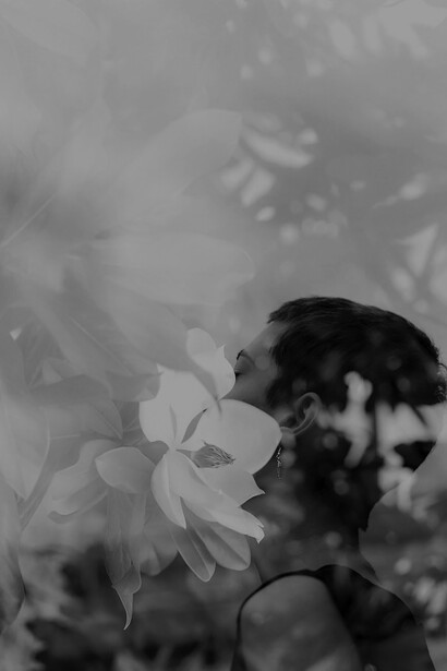 Amidst a sea of delicate white flowers, a woman stands elegantly, as if she is a living embodiment of the serene floral landscape
