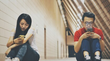 Dos jóvenes que se ignoran y prestan atención a sus teléfonos móviles