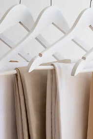 Light brown beige pants hanging on minimalist hangers, showcasing a sleek and simple style