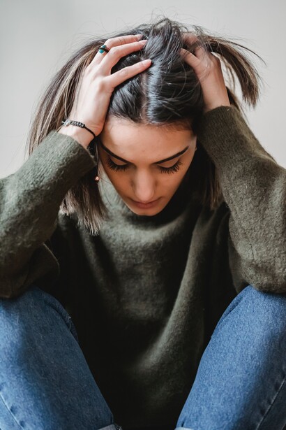Woman grabbing hair as she looks at the ground